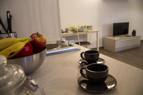 a bowl of fruit and two cups on a kitchen counter at Apartments Fewo in Bolzano