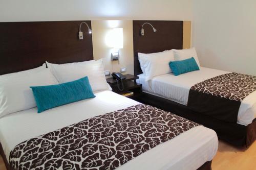 a hotel room with two beds with blue pillows at Hotel San Silvestre in Barrancabermeja