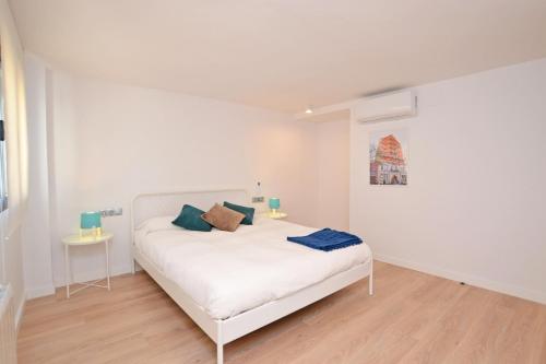 a white bedroom with a white bed and two tables at AticoColón21 in Alicante