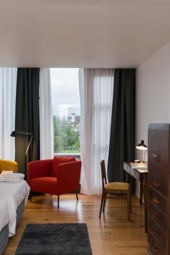 a bedroom with a bed and a red chair and a window at Quinta Nossa Senhora do Cabo in Lagoa