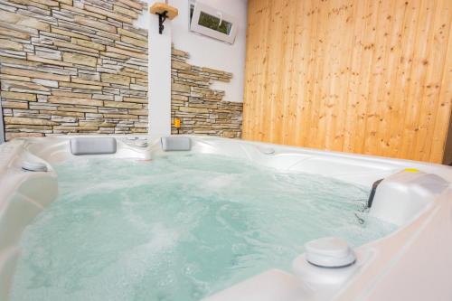 a jacuzzi tub in a bathroom with a stone wall at Apartments Ruzica in Pinezici