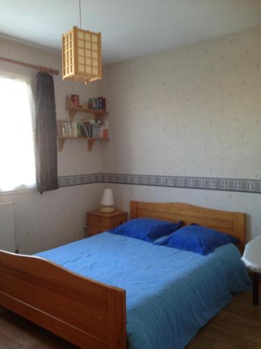 une chambre avec un lit avec des draps bleus et une fenêtre dans l'établissement La villa voyage, à La Rochelle