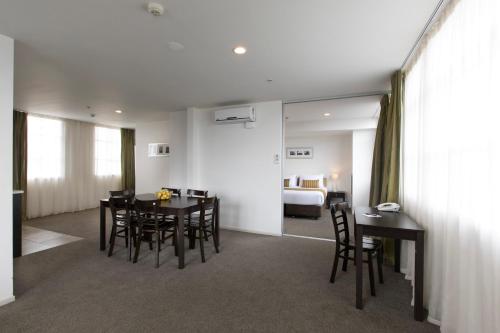 a dining room with a table and chairs and a bedroom at Quest on London in Hamilton