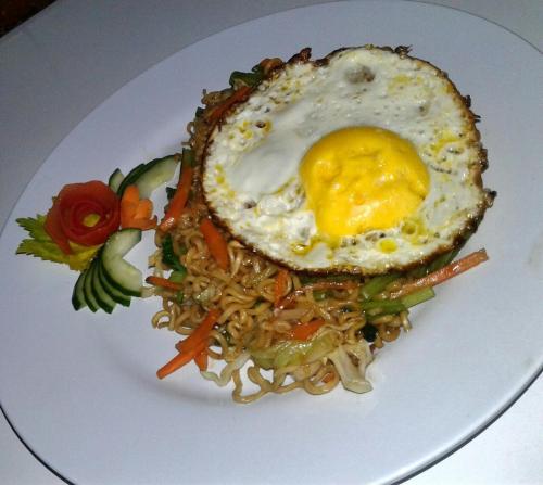 a plate of food with an egg on top of noodles at Gubug Balian Beach Bungalow in Selemadeg