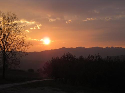 a sunset with the sun setting over a mountain at Cascina Giardini in Alba