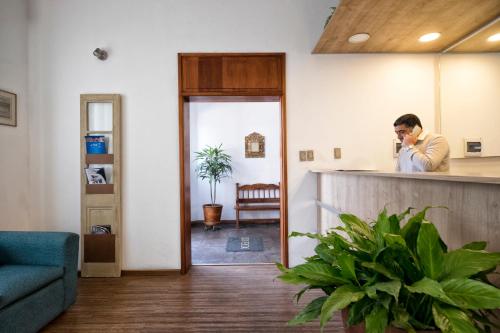 a man standing behind a counter talking on a cell phone at Sori Apartments in Lima