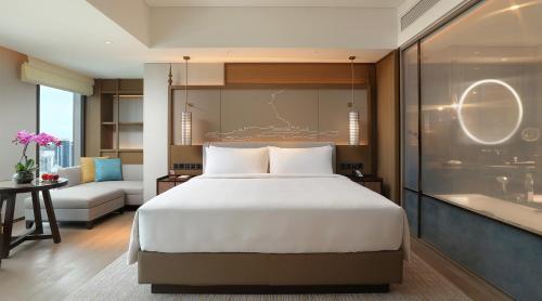 a bedroom with a large bed and a bath tub at Pan Pacific Yangon in Yangon