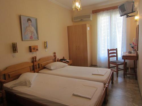 a bedroom with two beds and a table and a chair at Sandalis Hotel in Pythagoreio