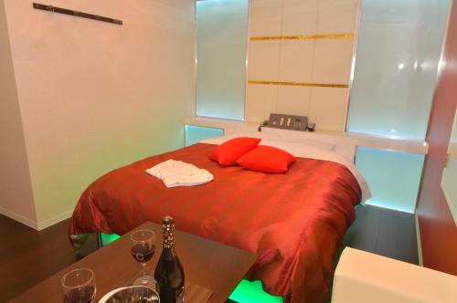 a room with a bed with red pillows and a table at Terrace M Yokota Bace ( Adult Only ) in Hakonegasaki