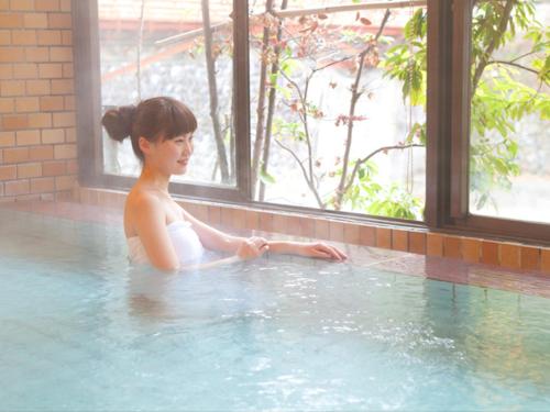 una joven sentada en una piscina en Atarashiya Ryokan en Tenkawa