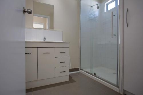 a white bathroom with a shower and a sink at Portland Holiday Village in Portland