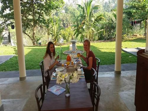 zwei Frauen sitzen an einem Tisch im Garten in der Unterkunft Pelli Riverine in Weligama