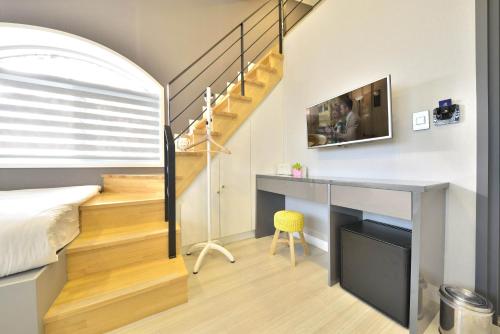 a bedroom with a bed and a desk and a staircase at With U Hotel & Guesthouse in Sokcho