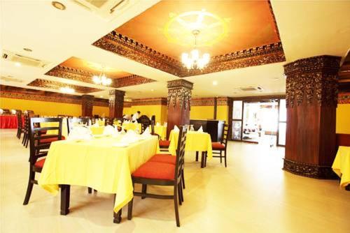 a restaurant with tables and chairs with yellow table cloth at Hotel Tibet International in Kathmandu