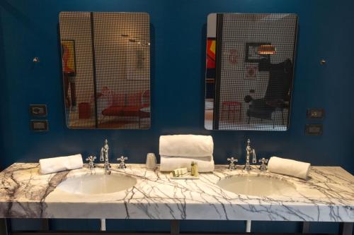 a blue bathroom with two sinks and two mirrors at Boutique Hotel Trieste - Adults Only in Verona
