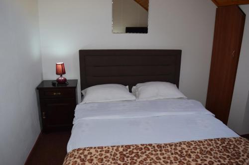 a bed with a black headboard and a lamp on a night stand at Pension Casa Samurai in Braşov