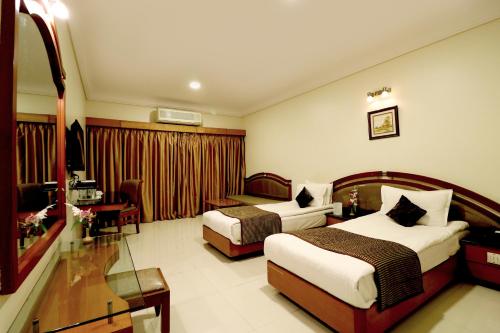 a hotel room with two beds and a desk at Hotel AGC in Aurangabad