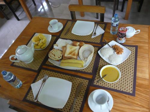 een houten tafel met borden met eten erop bij Silent Bungalow in Udawalawe