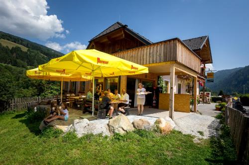 a group of people sitting at a table under a yellow umbrella at Da Bräuhauser in Stadl an der Mur