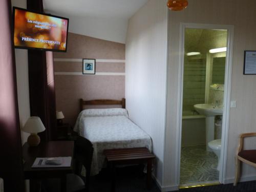 - une chambre avec un lit, un lavabo et une télévision dans l'établissement Hôtel Restaurant "Le Relais", à Courtenay