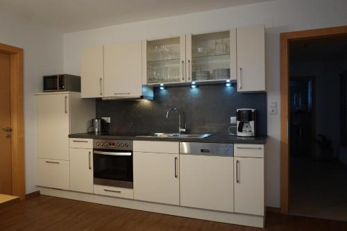 eine Küche mit weißen Schränken und einem Waschbecken in der Unterkunft Haus Panoramablick in Zellberg