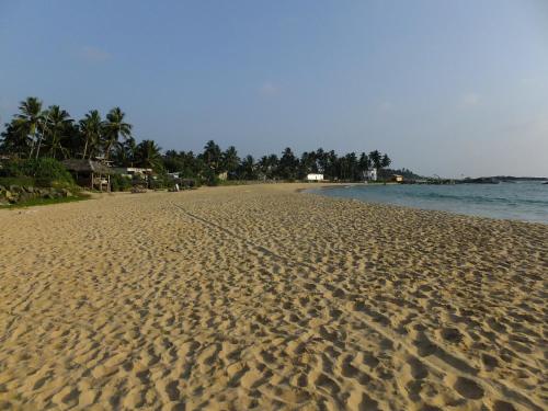 a beach with footprints in the sand and the water at Anjana Villa in Hikkaduwa