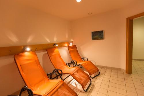 a row of orange chairs in a waiting room at Landhotel Maiergschwendt inkl Chiemgaukarte in Ruhpolding
