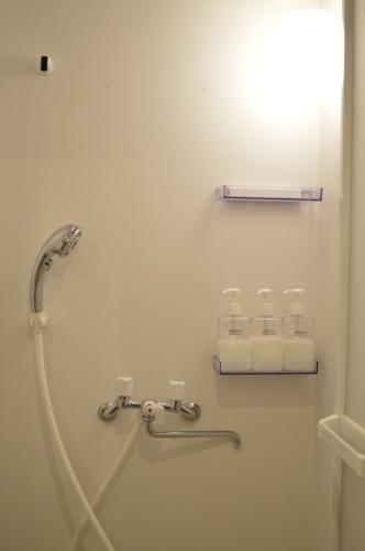 a bathroom with a shower with towels on a wall at R Guest House in Osaka