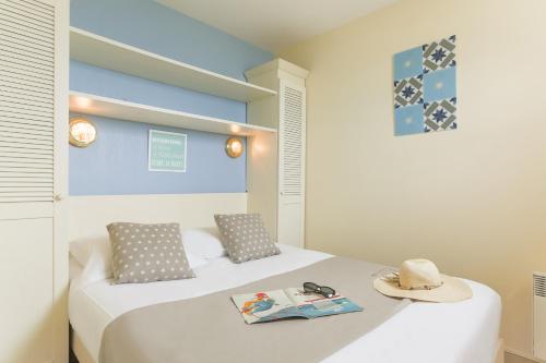 two beds in a room with a hat and a book at Résidence Pierre & Vacances Bleu Marine in Lacanau-Océan
