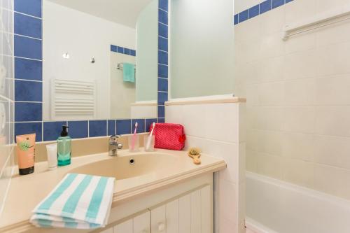 La salle de bains est pourvue d'un lavabo, d'un miroir et d'une baignoire. dans l'établissement Résidence Pierre & Vacances Bleu Marine, à Lacanau-Océan