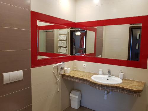a bathroom with a sink and a red mirror at Pokoje De Luxe Figaro in Płock