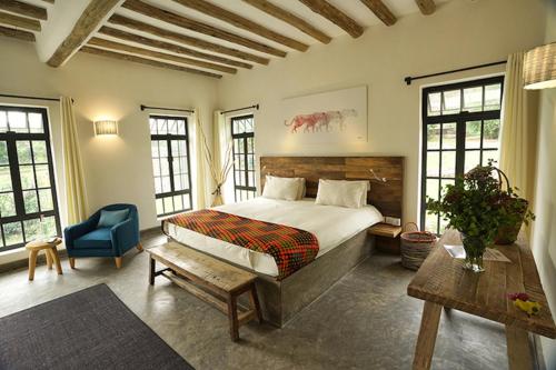 um quarto com uma cama grande e uma cadeira azul em Arusha Villa Karamu Coffee Estate em Usa River