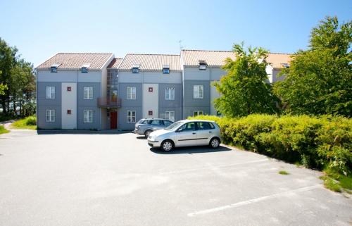 a building with two cars parked in a parking lot at Sjøsanden Ferietun in Mandal