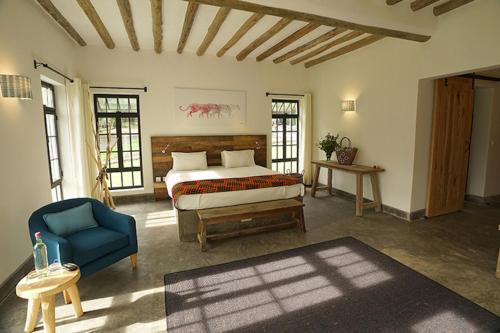 a bedroom with a bed and a blue chair at Arusha Villa Karamu Coffee Estate in Usa River