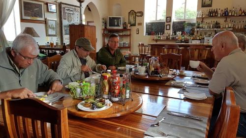 a group of men sitting around a wooden table at Angler and Antelope Guesthouse in Somerset East