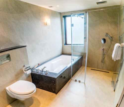 a bathroom with a tub and a toilet and a shower at The Ivy Anjuna in Anjuna