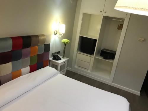 a bedroom with a white bed and a television at Hotel Sercotel Doña Carmela in Seville