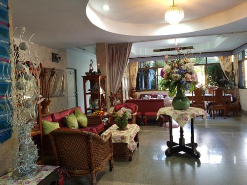 uma sala de estar com um vaso de flores sobre uma mesa em Wiang Inn Mansion em Chiang Mai