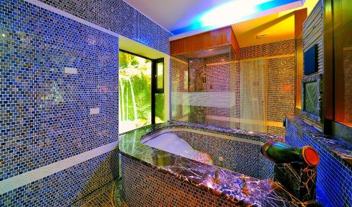 a blue tiled bathroom with a tub and a window at Hakodate Motel in Kaohsiung
