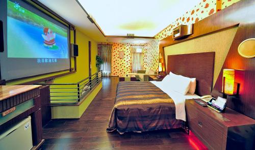 a hotel room with a bed and a flat screen tv at Hakodate Motel in Kaohsiung