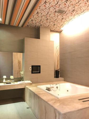 a large bathroom with a bath tub and a tv at Hiye Fashion Motel in Dounan