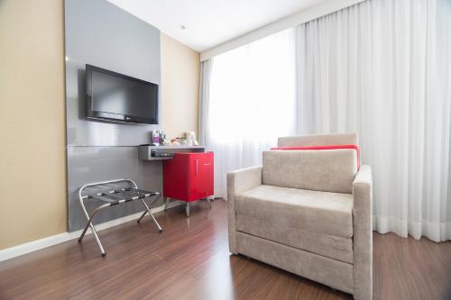 a living room with a chair and a tv at Mercure Sao Paulo Vila Olimpia in São Paulo