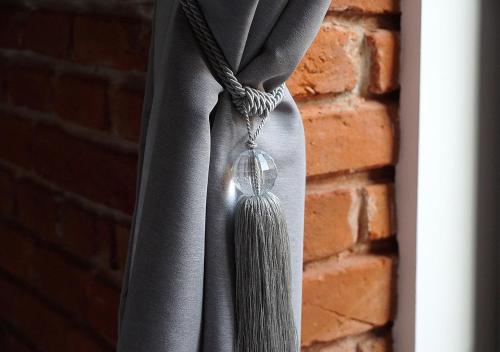a gray curtain with a tassel hanging from a window at Aparthotel Łódź 55 Piotrkowska in Łódź