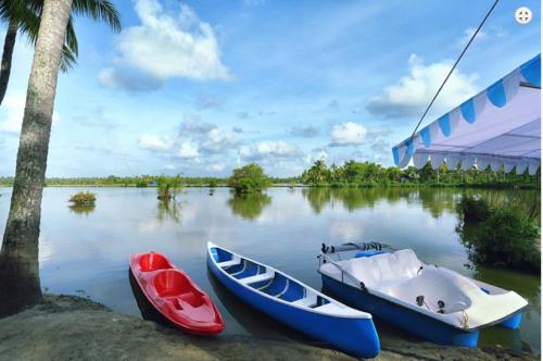 three boats sitting in the water next to a building at Indriya Sands in Cherai Beach