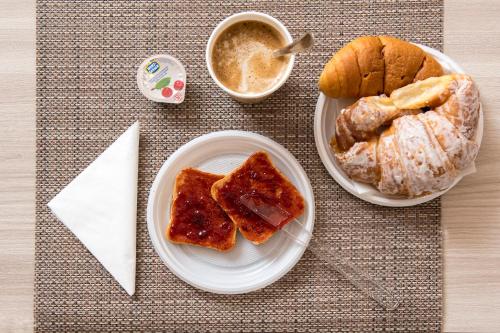 a table with two plates of food with bread and a cup of coffee at Domus Il Palio in Siena