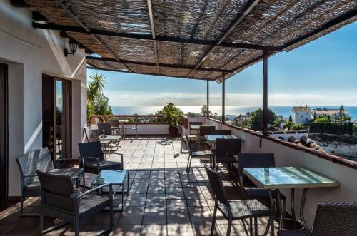 a patio with tables and chairs on a balcony at Hotel Rural Almazara in Frigiliana