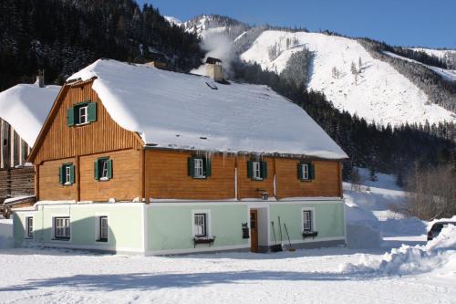 a house with a snow covered roof in the snow at Ferienwohnung Schaupphof in Donnersbachwald