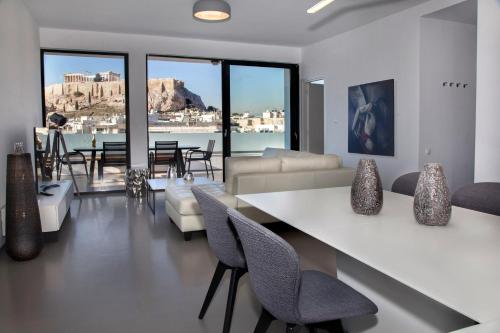 a living room with a couch and a table and chairs at Luxury Penthouse touching the Acropolis by GHH in Athens