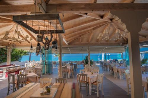 a dining room with tables and chairs and the ocean at WhiteSands Beach Resort in Paralia Vrachou