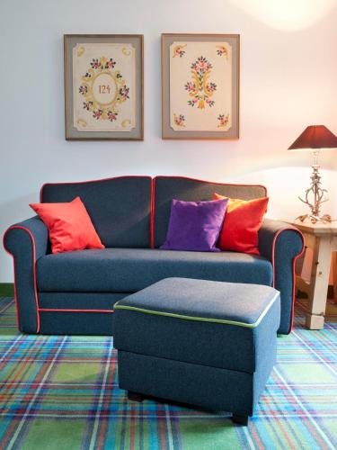 a blue couch with colorful pillows in a living room at Relais & Châteaux Gut Steinbach Hotel Chalets SPA in Reit im Winkl